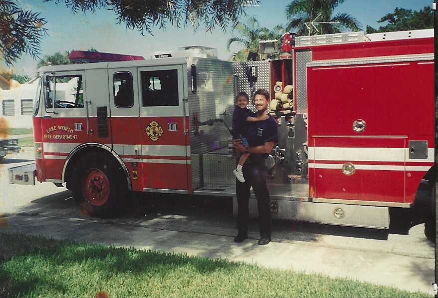 Founder Brian Johnson holding a child beside a red fire engine